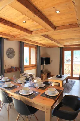 a large wooden table in a living room with chairs at Apartment Planards Centre Chamonix foot of the Planards Slopes in Chamonix-Mont-Blanc