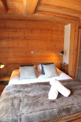 a large bed in a room with wooden walls at Apartment Planards Centre Chamonix foot of the Planards Slopes in Chamonix-Mont-Blanc