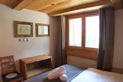 a bedroom with a bed and a window and a chair at Apartment Planards Centre Chamonix foot of the Planards Slopes in Chamonix-Mont-Blanc
