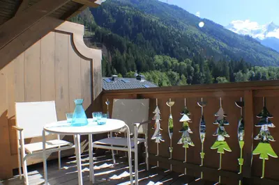 a table and chairs on a balcony with a mountain at Apartment Planards Centre Chamonix foot of the Planards Slopes in Chamonix-Mont-Blanc