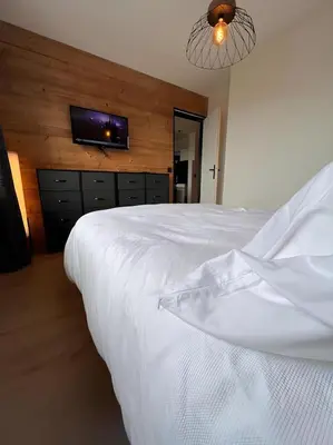 a bedroom with a white bed with a tv on the wall at Vue Mont blanc, ski et village in Combloux