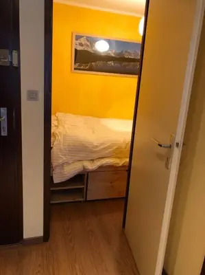 a small bedroom with a bed in a yellow wall at Chamonix centre - 2 pièces 32 m2 in Chamonix-Mont-Blanc
