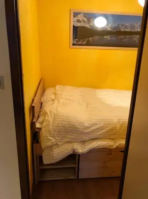 a small bed in a room with a yellow wall at Chamonix centre - 2 pièces 32 m2 in Chamonix-Mont-Blanc