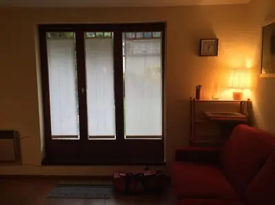 a living room with a door and a red couch at Chamonix centre - 2 pièces 32 m2 in Chamonix-Mont-Blanc