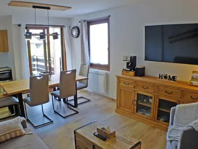 a living room with a table and a large screen television at Appartement rénové avec terrasse et parking, fibre incluse - FR-1-629-127 in Samoëns