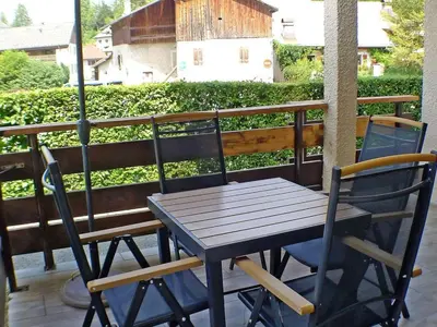 a wooden table and two chairs on a balcony at Appartement rénové avec terrasse et parking, fibre incluse - FR-1-629-127 in Samoëns