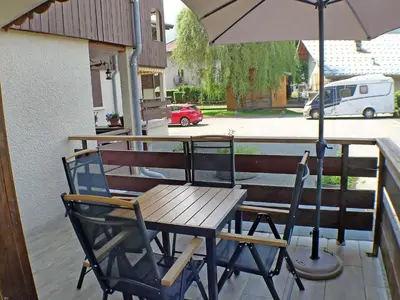 a wooden table and chairs with an umbrella on a porch at Appartement rénové avec terrasse et parking, fibre incluse - FR-1-629-127 in Samoëns