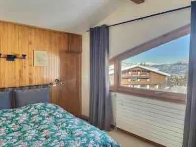 a bedroom with a bed and a large window at superbe appartement avec vue sur montagnes, calme in Megève