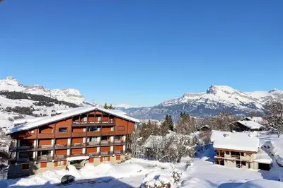 a building covered in snow with mountains in the background at superbe appartement avec vue sur montagnes, calme in Megève