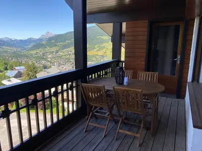 a wooden table and chairs on a balcony with a view at superbe appartement avec vue sur montagnes, calme in Megève