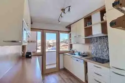 a large kitchen with white cabinets and wooden floors at superbe appartement avec vue sur montagnes, calme in Megève