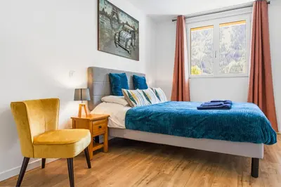 a bedroom with a bed and a chair and a window at Apartment Le Panoramic in Chamonix-Mont-Blanc