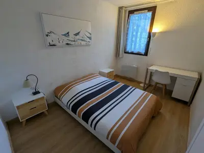 a bedroom with a bed and a desk and a window at Central spacious flat with private parking in Chamonix-Mont-Blanc
