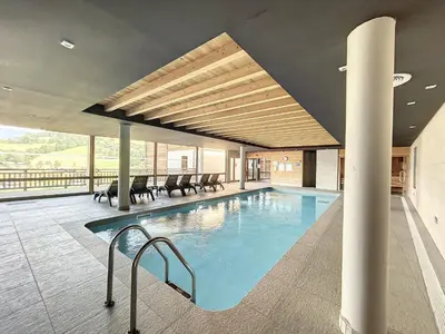 a swimming pool in a building with chairs and tables at Chalet de Luxe 6 Chambres avec Piscine et Bien-Être à Combloux - FR-1-560-107 in Combloux