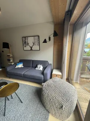 a living room with a blue couch and a table at Appartement standing face mont blanc piscine in Megève