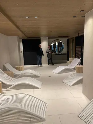 two people standing in a lobby with white chairs at Appartement standing face mont blanc piscine in Megève