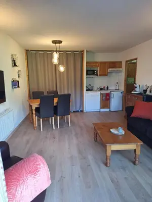 a living room with a couch and a table and a kitchen at Très bel Appartement Lumineux à Samoëns in Samoëns