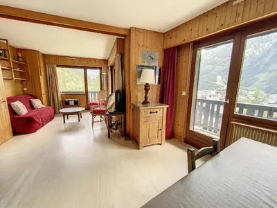 a living room with a red couch and a room withwindows at Caribou Lodge in Chamonix-Mont-Blanc