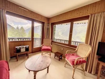 a living room with a table and chairs and windows at Caribou Lodge in Chamonix-Mont-Blanc