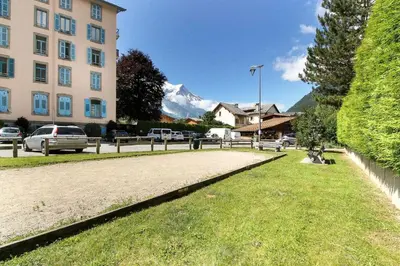 a park with a building and a mountain in the background at Clos des vorgeats 3 - Téléphérique, Terrain de Folf, Randonnée et Bus à la porte in Chamonix-Mont-Blanc