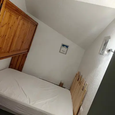 a small bedroom with a bed and a wooden cabinet at Appartement O'Contamines in Les Contamines-Montjoie