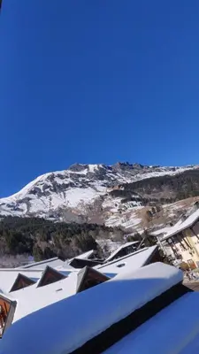 a snow covered mountain in the distance with houses and buildings at Appartement O'Contamines in Les Contamines-Montjoie