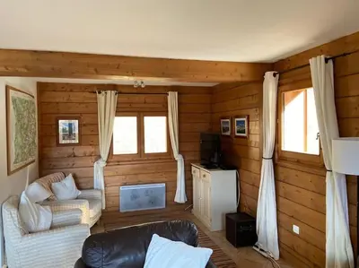a living room with wooden walls and a couch andwindows at Chalet Cannon- Mountain Getaway in Les Contamines-Montjoie