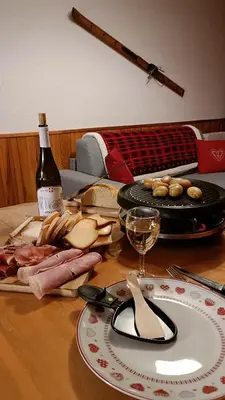 a table with a plate of food and a bottle of wine at Appartement pied des pistes - Samoëns 1600 in Samoëns