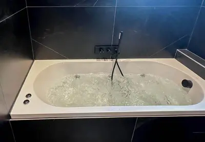 a bath tub filled with water in a bathroom at Masai Megeve in Megève
