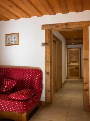 a red couch in a living room with a wooden ceiling at Gite Balnéo La Pomme de Pin in Sixt