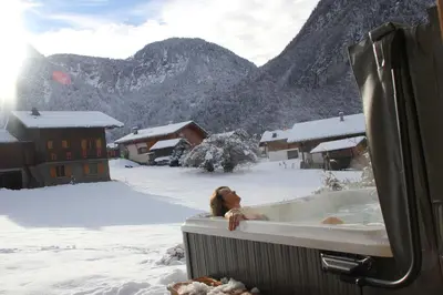 a woman in a hot tub in the snow at Gite Balnéo La Pomme de Pin in Sixt