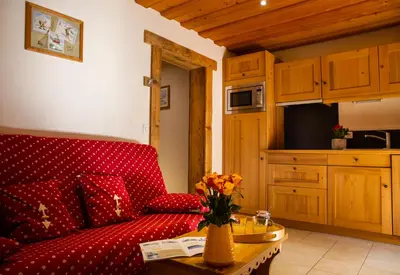 a living room with a red couch and a table at Gite Balnéo La Pomme de Pin in Sixt