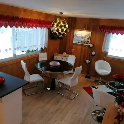 a dining room with a table and white chairs at Le p'tit Rubis in Chamonix-Mont-Blanc
