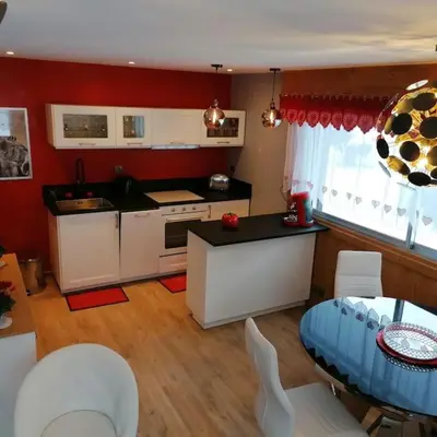 a kitchen with white cabinets and a table and chairs at Le p'tit Rubis in Chamonix-Mont-Blanc