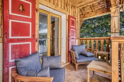 a porch with two chairs and a table and a red door at Panorama du Mont-Blanc- Spacious and ideally located 1 bedroom apartment in Chamonix-Mont-Blanc