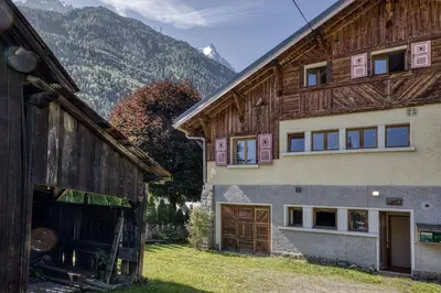 a house and a barn with mountains in the background at Panorama du Mont-Blanc- Spacious and ideally located 1 bedroom apartment in Chamonix-Mont-Blanc