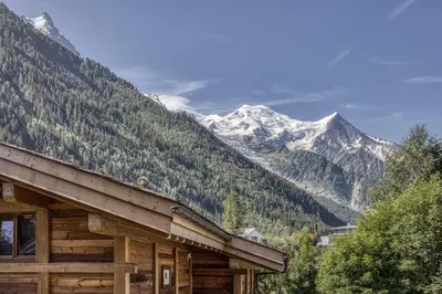 a log cabin with mountains in the background at Panorama du Mont-Blanc- Spacious and ideally located 1 bedroom apartment in Chamonix-Mont-Blanc