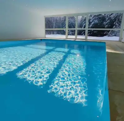 a swimming pool with blue water and two windows at SKI AUX PIEDS et PIEDS DANS L'EAU in Les Contamines-Montjoie