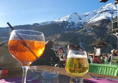 two glasses of beer sitting on a table with a mountain at SKI AUX PIEDS et PIEDS DANS L'EAU in Les Contamines-Montjoie
