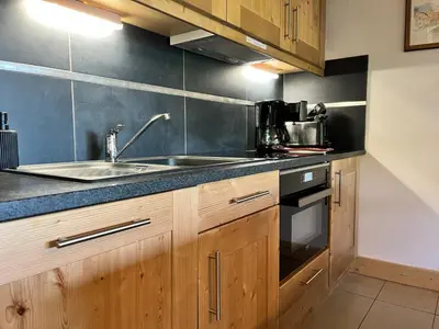a kitchen with wooden cabinets and a sink at Magnifique duplex 3 chambres près du Grand Massif, wifi et garage - FR-1-624-136 in Samoëns