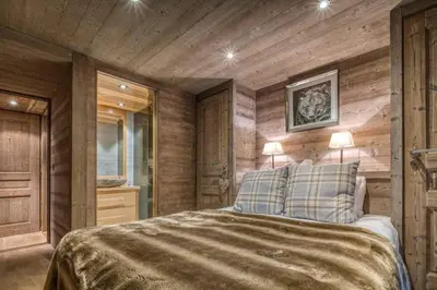 a bedroom with wooden walls and a bed with two lamps at Chalet Canopée in Demi-Quartier