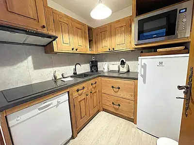 a kitchen with wooden cabinets and a white refrigerator at Appartement avec balcon, parking et animaux acceptés à Chamonix - FR-1-343-245 in Chamonix-Mont-Blanc