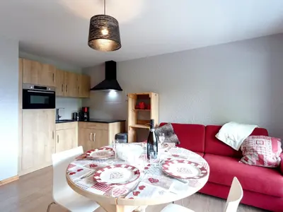 a small kitchen with a table and a red couch at Studio Les Tétras by Interhome in Saint-Gervais-les-Bains