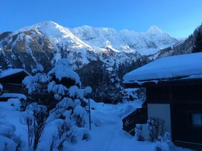a snow covered mountain in front of a house at Apartment Village des Oursons Chalet A4 by Interhome in Chamonix-Mont-Blanc