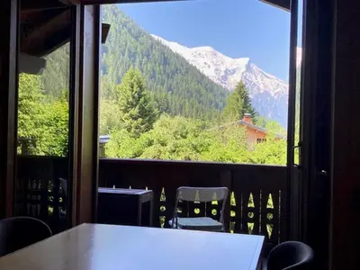 a table and chairs on a balcony with a view of a mountain at Apartment Village des Oursons Chalet A4 by Interhome in Chamonix-Mont-Blanc