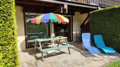 a table and two chairs and an umbrella on a patio at Appartement en rez de jardin vue montagne in Les Contamines-Montjoie