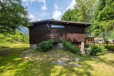 a small cabin with a wooden door in the grass at Rustic chalet with garden in Chamonix in Chamonix-Mont-Blanc