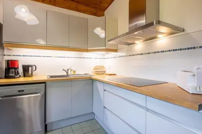 a kitchen with white cabinets and a wooden counter top at Rustic chalet with garden in Chamonix in Chamonix-Mont-Blanc