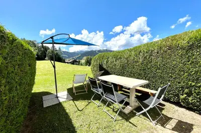 a table and chairs with an umbrella in the grass at Nid d'Arbois in Megève