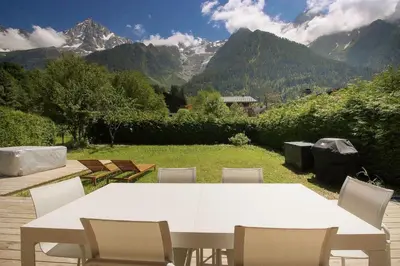 a white table and chairs with mountains in the background at Chalet Béchar Le Magnifique- Garden - Sauna & Jacuzzi in Les Houches